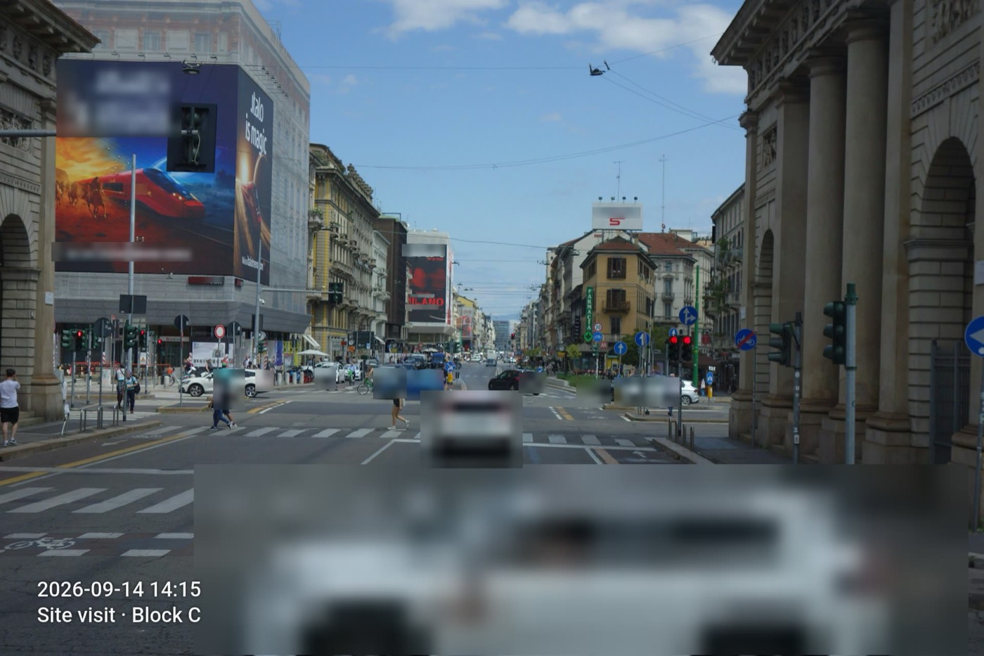 A busy city street with every face, person and licence plate blurred out, and a date and site stamp in the corner.